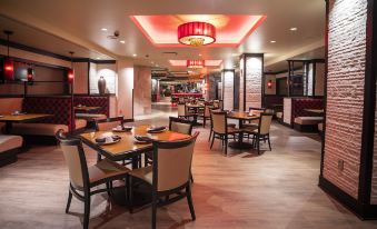 a modern restaurant with wooden tables and chairs , red pendant lights , and large windows , giving it a bright and inviting atmosphere at The Inn at Charles Town / Hollywood Casino