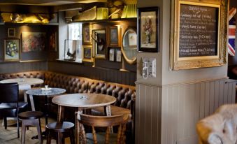 a restaurant with wooden tables and chairs , a bench , and various framed pictures on the wall at The White Horse