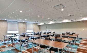 a large , empty conference room with multiple rows of tables and chairs arranged for meetings or events at Home2 Suites by Hilton la Porte