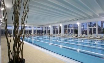 a large indoor swimming pool surrounded by lounge chairs , where people are relaxing and enjoying their time at Hotel Belvedere