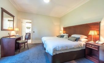a modern hotel room with two beds , white bedding , and blue carpeting , along with a desk and nightstand at Cumbria Grand Hotel