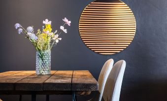 a dining room with a wooden dining table , two chairs , and a vase of flowers on the table at Hotel-B