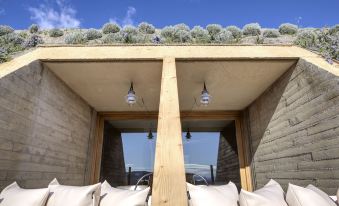 a wooden structure with white pillows and a hanging light , under which hangs a grassy area at Trossos del Priorat