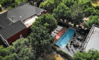an aerial view of a backyard with a pool surrounded by trees , including a large house and several trees at Ruby Rose