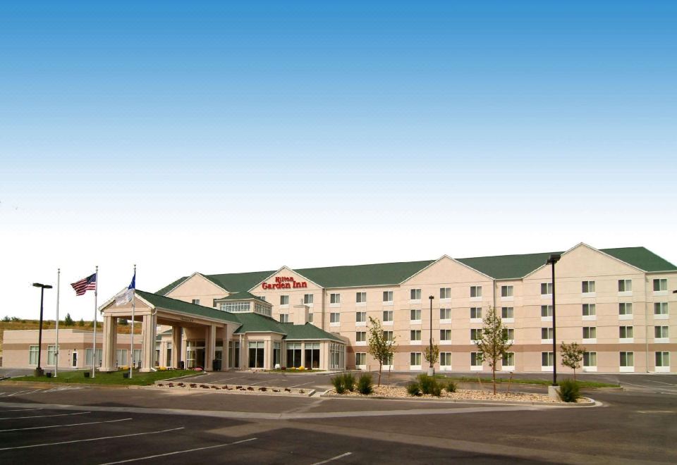 a large hotel with a red sign and american flag is shown in the image at Hilton Garden Inn Casper