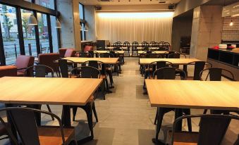 a dining area with wooden tables and chairs , as well as a television mounted on the wall at Green Rich Hotel Kurume