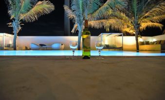 a bottle of wine and two wine glasses are placed near a pool , with palm trees in the background at Dolphin Beach Resort