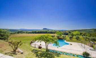 a large backyard with a swimming pool surrounded by green grass and trees , creating a serene and relaxing atmosphere at Chambre d'Hotes