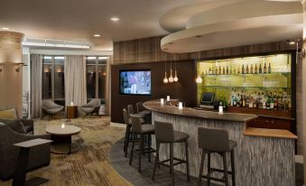 a modern bar with a curved counter , stools , and a television mounted on the wall at Courtyard Middletown Goshen