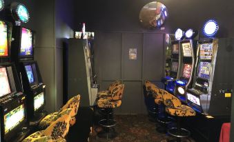 a room filled with various arcade games , including slot machines and pinball machines , set against a dark wall at Hotel Kerwick