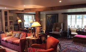 a cozy living room with a large couch , chairs , and a television mounted on the wall at Bridge Cottage