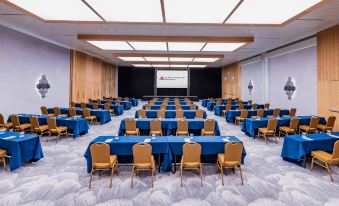 a large conference room with rows of tables and chairs , a screen at the front , and wooden flooring at Curacao Marriott Beach Resort