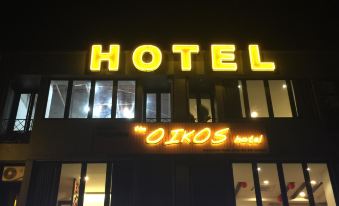 "a large building with a neon sign that says "" hotel "" in multiple languages , such as english and chinese" at The Oikos Hotel