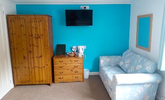 a small living room with a blue wall , a wooden cabinet , a couch , and a tv at Bartles Lodge