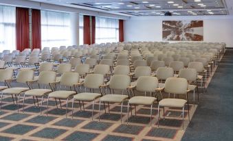 a large conference room with rows of chairs arranged in a semicircle , ready for an event at Steigenberger Airport Hotel Amsterdam