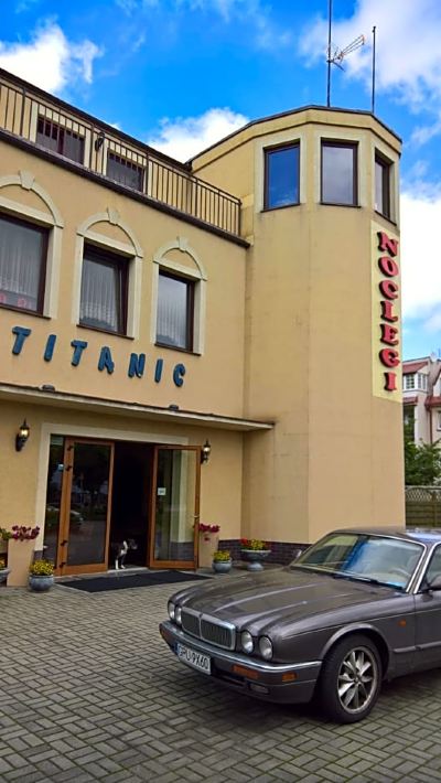 "a car is parked in front of a building with the words "" titanic "" and "" hoch neuer hotel ""." at Titanic