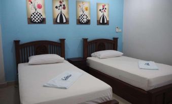 a small room with two twin beds , one on each side of the room , and a painting on the wall at Rimmueng Resort