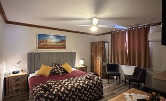 a cozy bedroom with a bed , a desk , and a tv . the room is well - decorated and features wooden floors and modern furniture at Brooklyn Motel