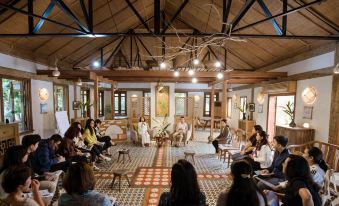 a group of people are sitting in a room with wooden beams and chairs , looking at each other at Tam Coc Garden Resort