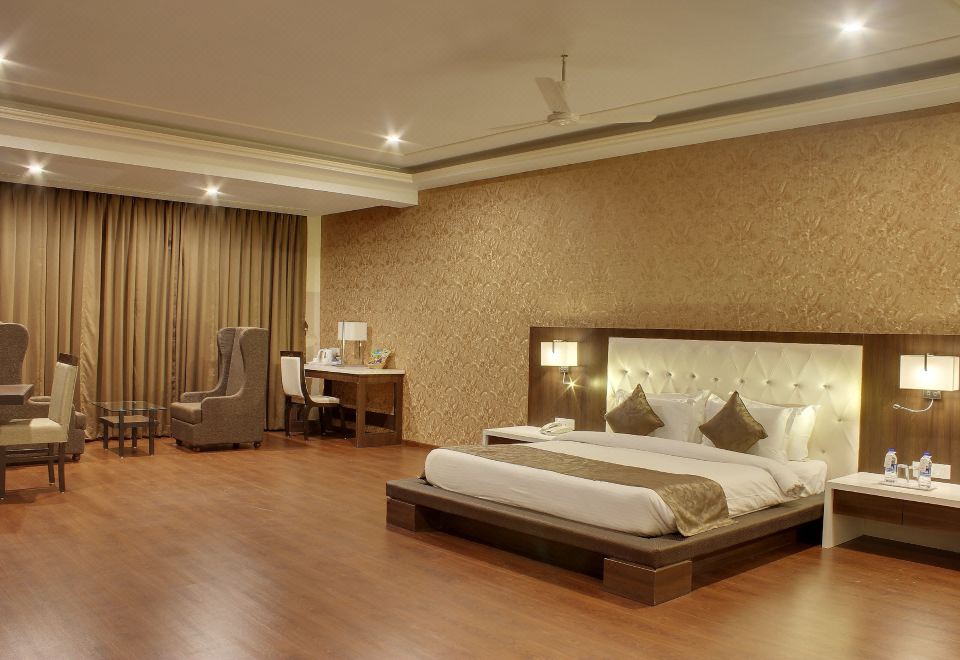 a large bed with white linens and brown pillows is in a room with wooden floors , a desk , and a chair at Hotel Lake View