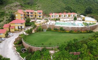 an aerial view of a resort with multiple buildings and a pool surrounded by greenery at River Rock Resort