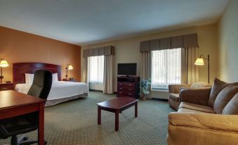 a spacious hotel room with a king - sized bed , a couch , and a television . also a dining table in the room at Hampton Inn & Suites Denver Littleton