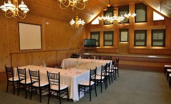 a large dining room with wooden walls and a high ceiling , decorated with a chandelier and a table set for a formal dinner at Eagle Mountain House and Golf Club