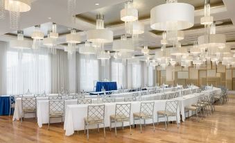 a large dining room with a long table covered in white tablecloths , surrounded by chairs at Allegria Hotel
