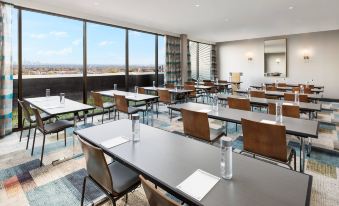 a large , empty conference room with multiple tables and chairs , ready for meetings or events at The MC Hotel, Autograph Collection