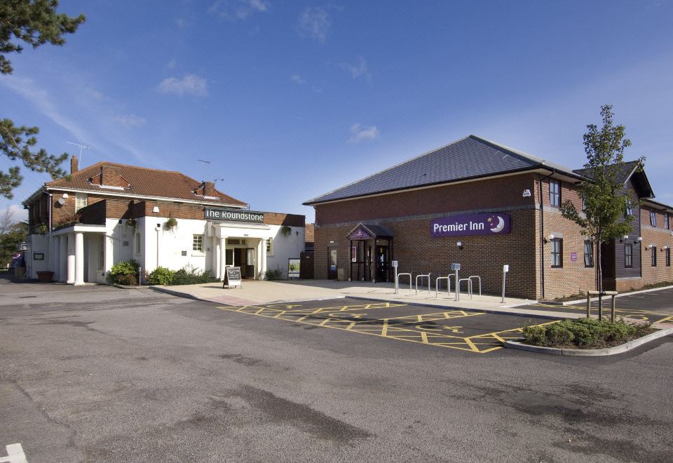 a premier inn building with a sign above the entrance , surrounded by trees and other buildings at Premier Inn Littlehampton