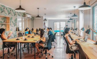 a group of people working at desks in an office space with multiple computers and large windows at Selina Jaco