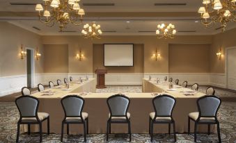 a conference room set up for a meeting , with chairs arranged in rows and a projector on the wall at Rosewood Bermuda