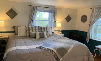 a well - decorated bedroom with a large bed , multiple pillows , and curtains , as well as a window with a view of trees at The Birchwood Inn