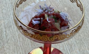 a gold - framed glass filled with red meat , possibly lamb , placed on a dining table , accompanied by a wine glass at Cambridge House Breakfast & Bed