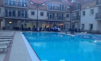 a large swimming pool with a red tile border and people sitting at tables in the background at Apartments Light