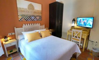 a bedroom with a large bed , white sheets , and a television on a wooden stand at La Esperanza