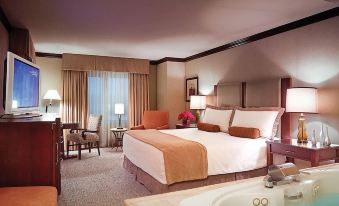 a large bed with a white and orange blanket is in the middle of a room with a bathtub and lamps at Ameristar Casino Hotel Council Bluffs