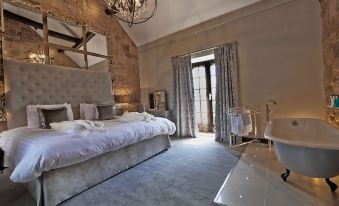 a large , elegant bedroom with a white bed and multiple pillows , a chandelier hanging from the ceiling , and a window with curtains at Horsley Lodge