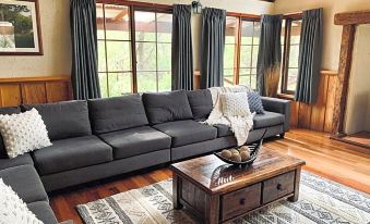 a living room with a large grey couch and a coffee table in front of a window at William Bay Cottages