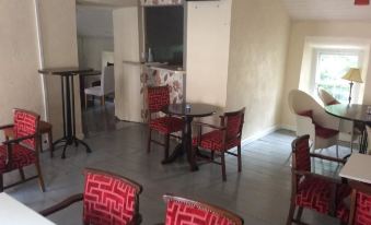 a room with red chairs and tables , a television on the wall , and an air conditioner at The Loft