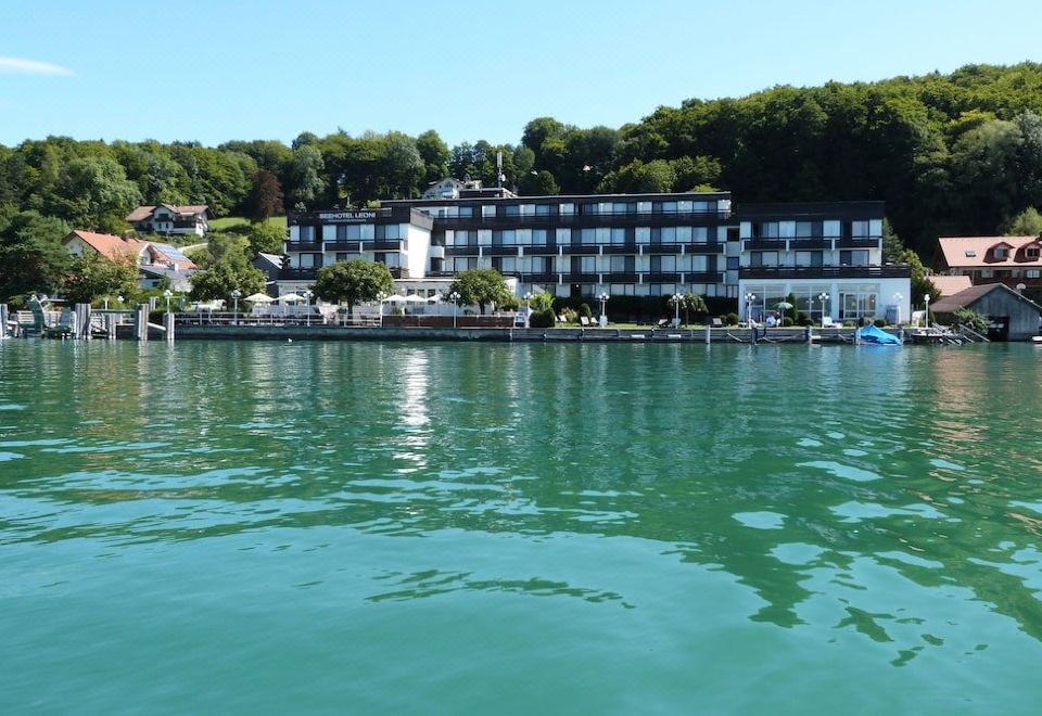 a large hotel situated on the shore of a lake , surrounded by trees and boats at Seehotel Leoni