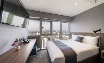The bedroom features large windows and a balcony with a city view, but the bed is unmade at Layers The Luxurious Hotel