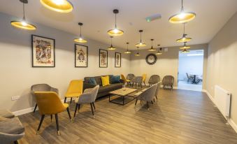 a modern , minimalist living room with wooden flooring and yellow chairs , surrounded by white walls and large windows at 42 Apart-Hotel