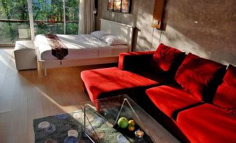 a living room with a red couch , white bed , and a glass coffee table in front of the window at Suan Muang Porn