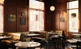 a modern , well - lit dining room with wooden walls and tables , surrounded by green sofas and chairs at Graduate Berkeley