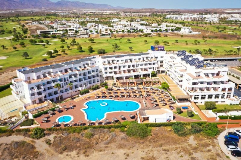 aerial view of a resort with a large pool surrounded by multiple buildings and a golf course at Ohtels Cabogata