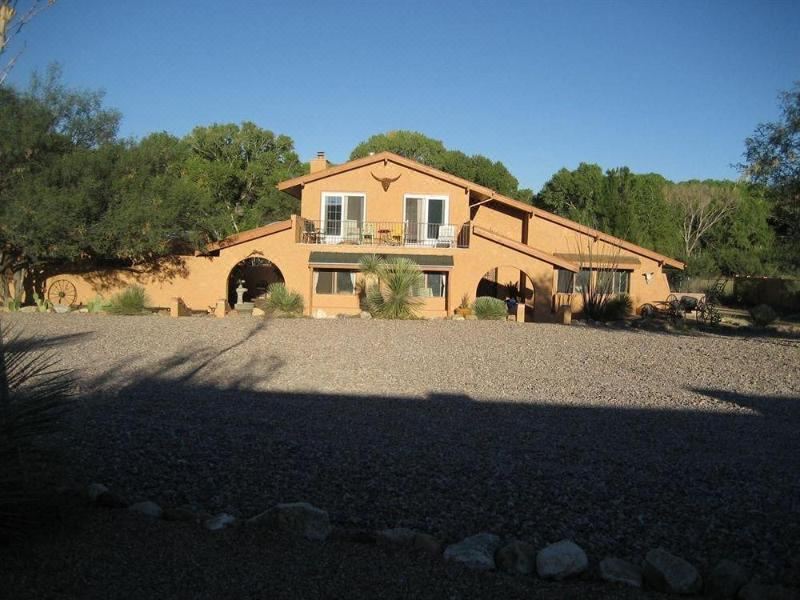 a large , two - story house with a brown exterior and white trim , surrounded by trees and gravel at Lazy Dog Ranch