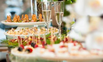 a dining table with a variety of appetizers and drinks , accompanied by two champagne flutes at Yes Hotel