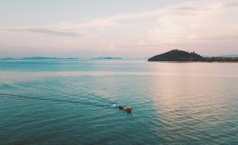 a boat is sailing in the middle of a large body of water , with an island visible in the background at Island Escape Burasari