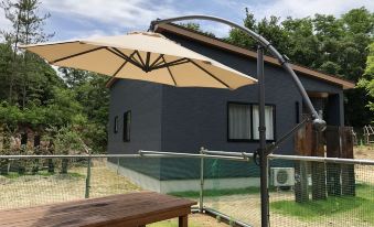 a wooden bench and a large umbrella are set up in front of a house at Cottage Sunset-Village